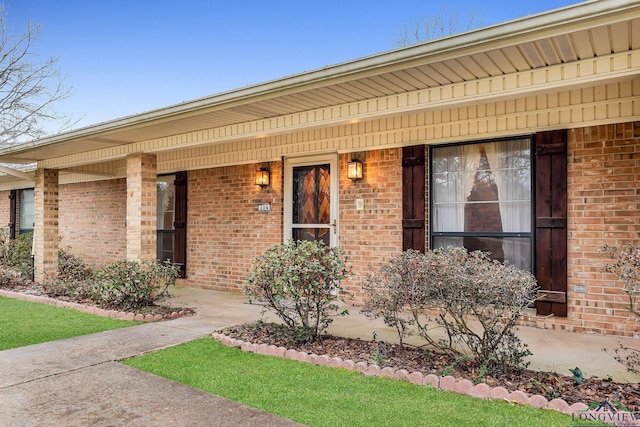 doorway to property with covered porch and brick siding