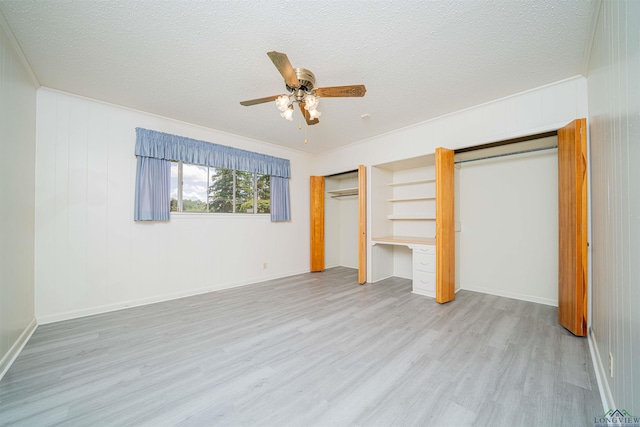 201 Bronco Ln, Linden, TX 75563 - unfurnished bedroom with two closets, light wood-style floors, a textured ceiling, and ceiling fan