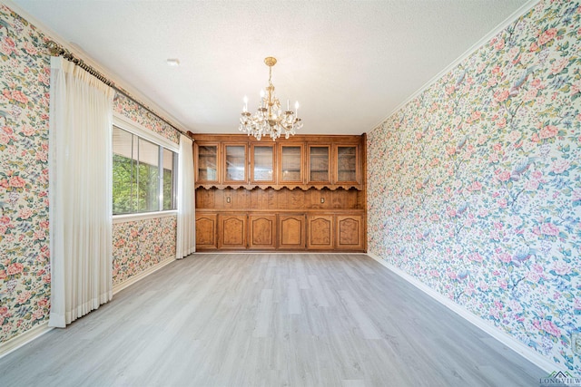 201 Bronco Ln, Linden, TX 75563 - unfurnished dining area featuring wallpapered walls, a chandelier, light wood-style floors, ornamental molding, and a textured ceiling