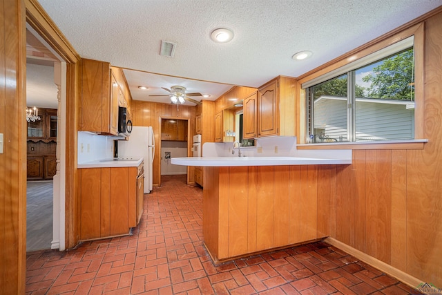 201 Bronco Ln, Linden, TX 75563 - kitchen featuring brick flooring, black microwave, light countertops, a peninsula, and a textured ceiling