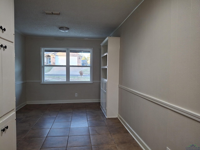 tiled empty room featuring a textured ceiling