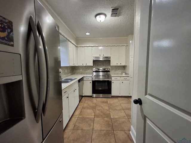 kitchen featuring white cabinetry, stainless steel appliances, tasteful backsplash, a textured ceiling, and light tile patterned floors