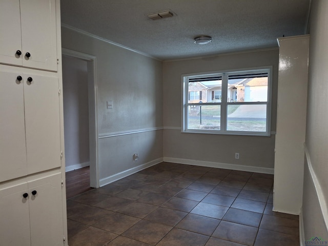 tiled spare room featuring a textured ceiling and ornamental molding