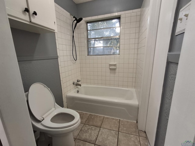 bathroom with tile patterned flooring, toilet, and tiled shower / bath