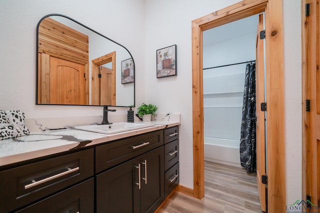 bathroom with wood-type flooring, shower / bath combination with curtain, and vanity