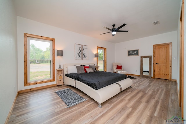 bedroom with ceiling fan, multiple windows, and light wood-type flooring