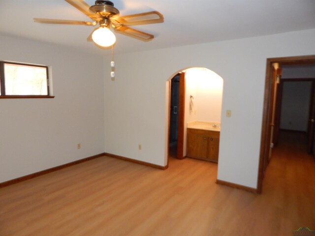 2231 W Stae Highway 154, Gilmer, TX 75644 - unfurnished bedroom featuring arched walkways, light wood finished floors, a sink, and baseboards