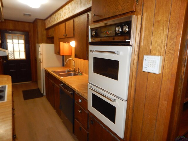 2231 W Stae Highway 154, Gilmer, TX 75644 - kitchen featuring light countertops, light wood-style floors, a sink, wood walls, and white appliances