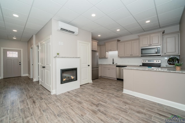 kitchen featuring light stone countertops, sink, a wall mounted air conditioner, decorative backsplash, and appliances with stainless steel finishes