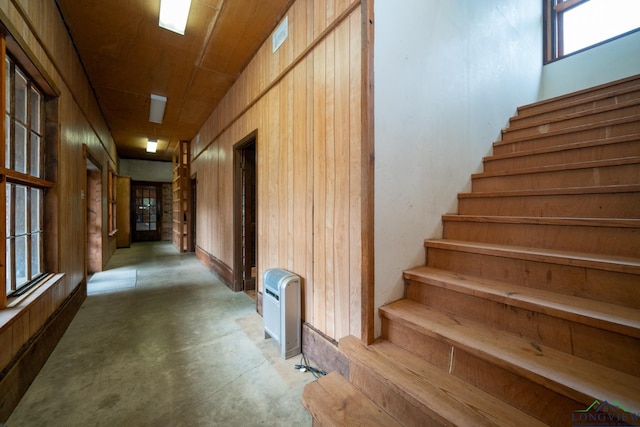 corridor featuring concrete flooring and wooden walls