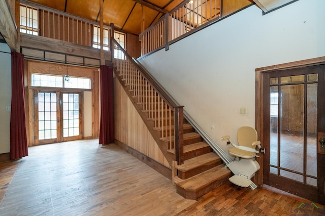 stairs with a wealth of natural light, french doors, hardwood / wood-style floors, and a high ceiling