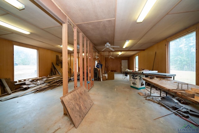 basement with a workshop area, ceiling fan, and wooden walls