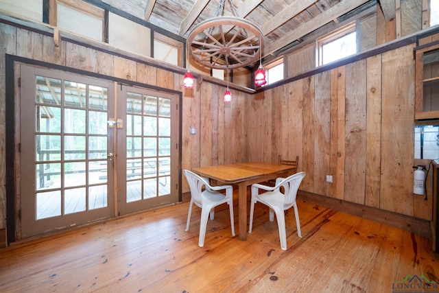 dining space with beamed ceiling, hardwood / wood-style floors, wooden walls, and wood ceiling