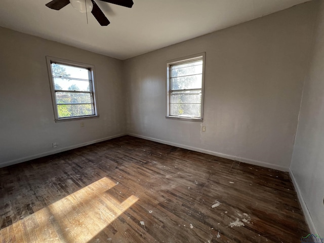 unfurnished room featuring a healthy amount of sunlight, ceiling fan, and dark wood-type flooring