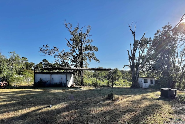 view of yard featuring central AC unit and a storage shed