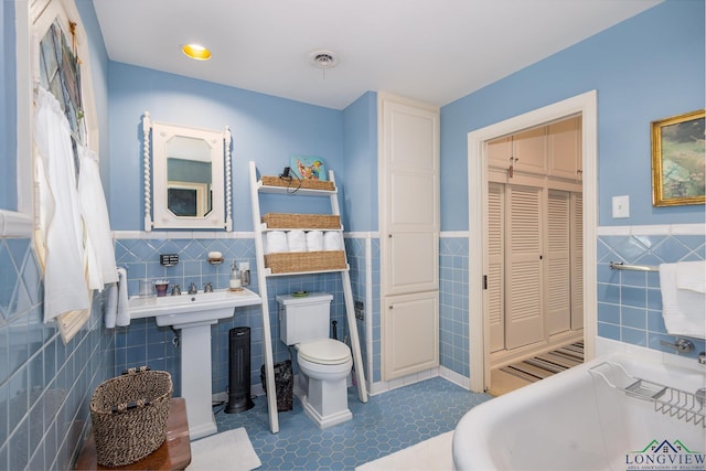 2003 Broadway Blvd, Kilgore, TX 75662 - full bathroom with tile walls, wainscoting, a closet, and a tub