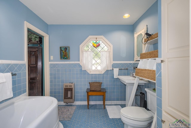 2003 Broadway Blvd, Kilgore, TX 75662 - bathroom featuring heating unit, tile walls, a wainscoted wall, a bath, and tile patterned flooring