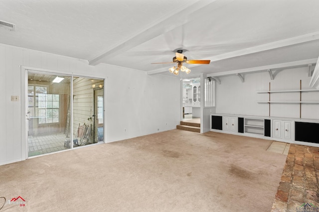 unfurnished living room with carpet, visible vents, ceiling fan, and beamed ceiling