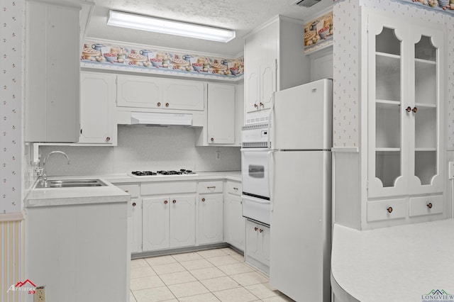 kitchen with white appliances, under cabinet range hood, white cabinetry, and light countertops