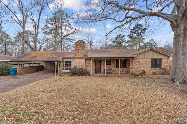 ranch-style house featuring aphalt driveway, brick siding, a chimney, a front yard, and an attached carport