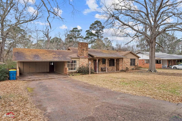 ranch-style house featuring a chimney, aphalt driveway, and a carport