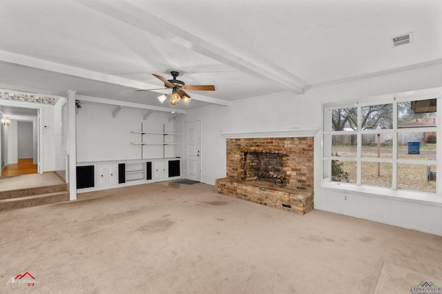 unfurnished living room featuring carpet floors, visible vents, stairway, a brick fireplace, and beamed ceiling