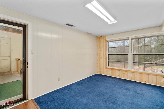 unfurnished room with visible vents and wood walls