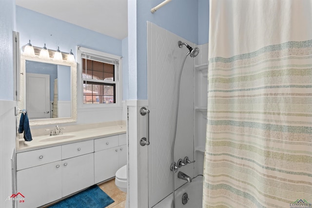 bathroom featuring toilet, a wainscoted wall, shower / tub combo, vanity, and tile patterned floors