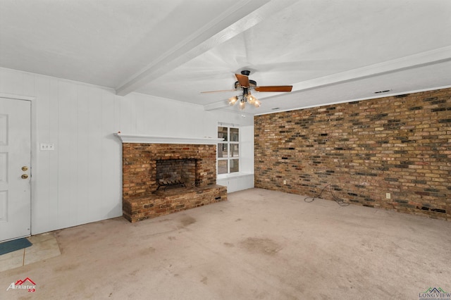 unfurnished living room with carpet, a fireplace, ceiling fan, brick wall, and beamed ceiling