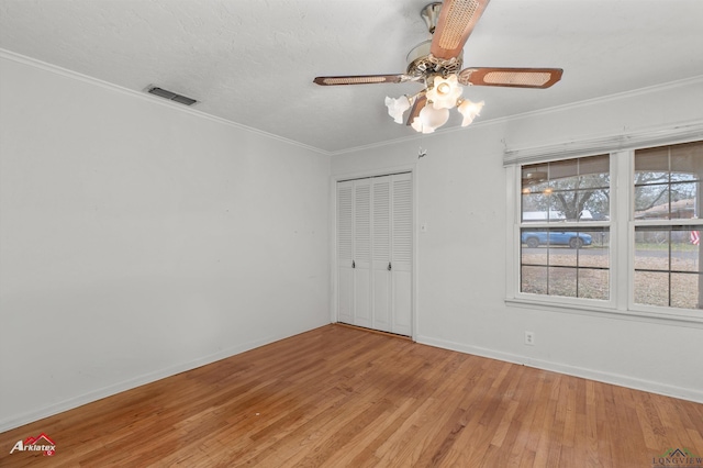 unfurnished bedroom featuring crown molding, a closet, visible vents, and wood finished floors