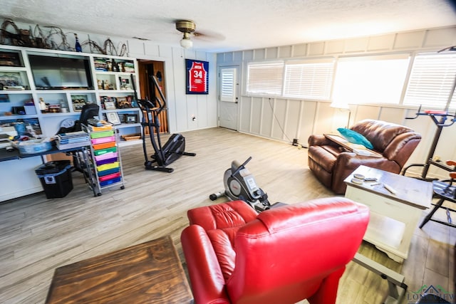 living room featuring wood-type flooring, a textured ceiling, and ceiling fan