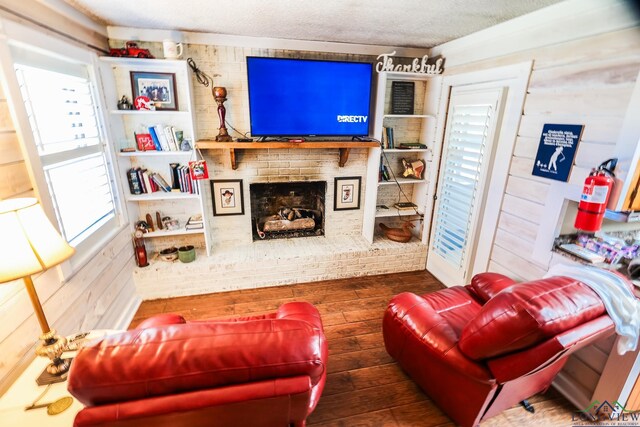 living room featuring dark hardwood / wood-style floors, a fireplace, a textured ceiling, and wooden walls