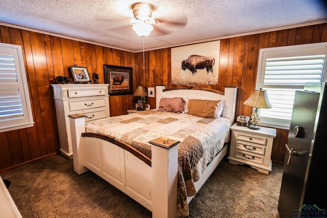 bedroom featuring dark colored carpet, ceiling fan, wood walls, and a textured ceiling