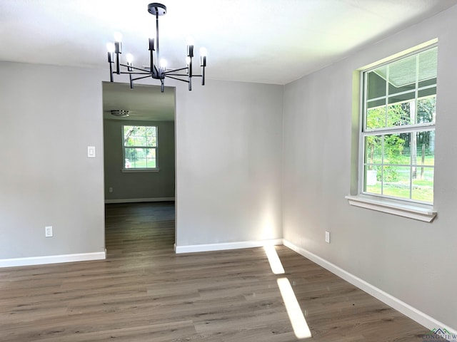 unfurnished dining area featuring an inviting chandelier and dark wood-type flooring