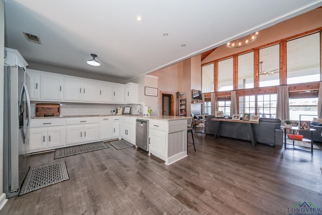 kitchen with backsplash, kitchen peninsula, appliances with stainless steel finishes, light stone counters, and white cabinetry