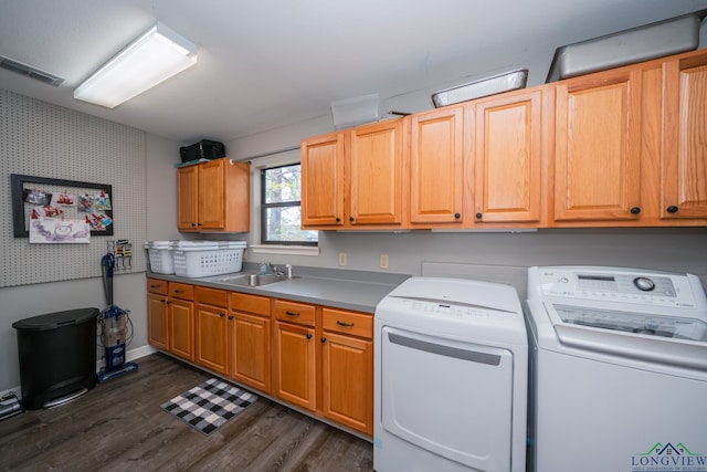 washroom featuring cabinets, sink, dark wood-type flooring, and washing machine and clothes dryer