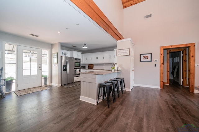 kitchen with light stone counters, kitchen peninsula, a breakfast bar area, white cabinets, and appliances with stainless steel finishes