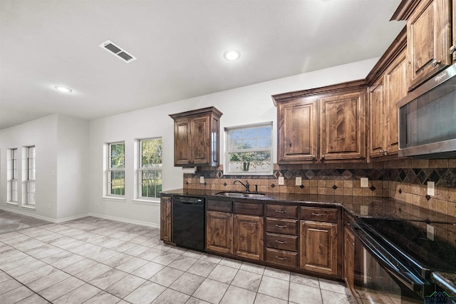 kitchen featuring tasteful backsplash, dark stone counters, sink, black appliances, and light tile patterned floors