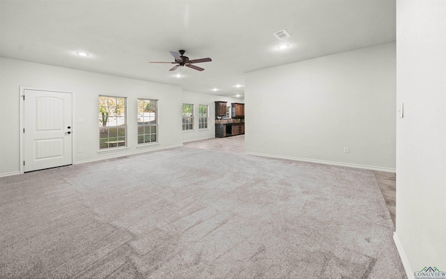 unfurnished living room featuring ceiling fan and light carpet