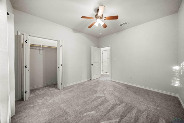 unfurnished bedroom with a closet, light colored carpet, and ceiling fan