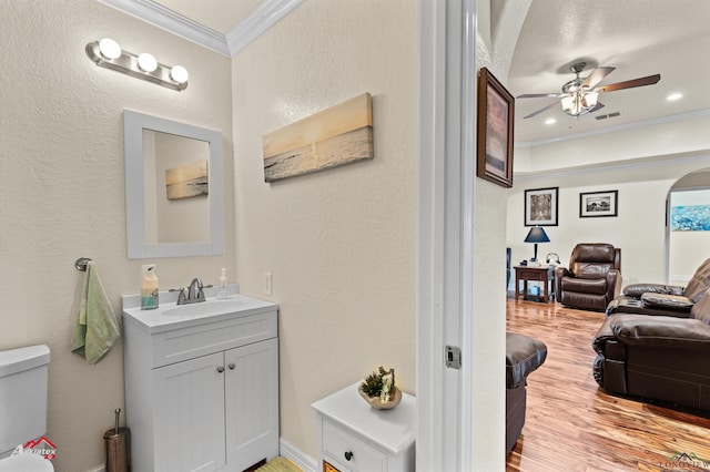 bathroom with ceiling fan, hardwood / wood-style floors, vanity, ornamental molding, and toilet