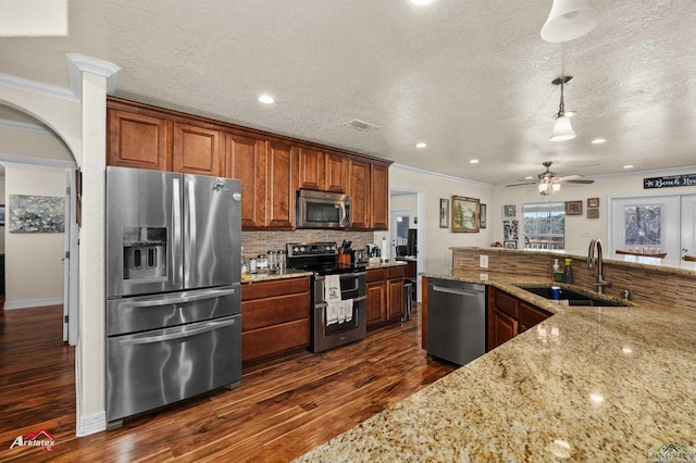 kitchen featuring sink, dark hardwood / wood-style flooring, pendant lighting, stainless steel appliances, and light stone countertops