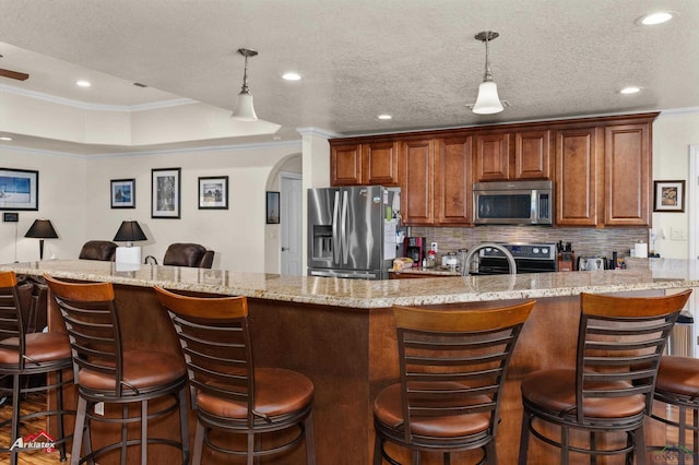 kitchen featuring ornamental molding, appliances with stainless steel finishes, a kitchen bar, and decorative backsplash