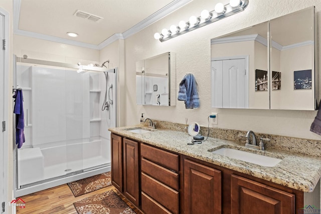 bathroom featuring ornamental molding, wood-type flooring, an enclosed shower, and vanity