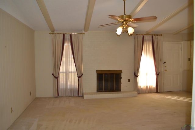 unfurnished living room featuring beamed ceiling, ceiling fan, carpet flooring, and a fireplace