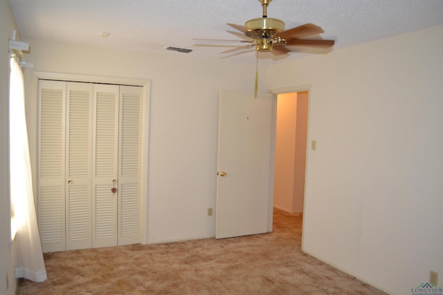 unfurnished bedroom with ceiling fan, light carpet, a closet, and a textured ceiling