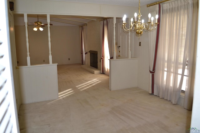 empty room with ceiling fan with notable chandelier and light carpet