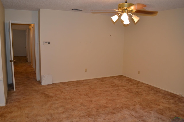 spare room featuring ceiling fan, light carpet, and a textured ceiling