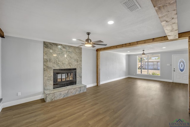 unfurnished living room with beam ceiling, ceiling fan, a high end fireplace, and wood-type flooring