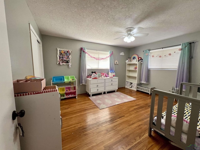 1523 Young St, Henderson, TX 75654 - bedroom featuring a textured ceiling, wood finished floors, a closet, baseboard heating, and ceiling fan